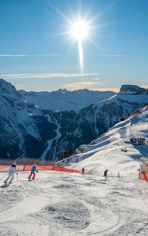 Ski run with skiers and safety nets and snow-covered mountains