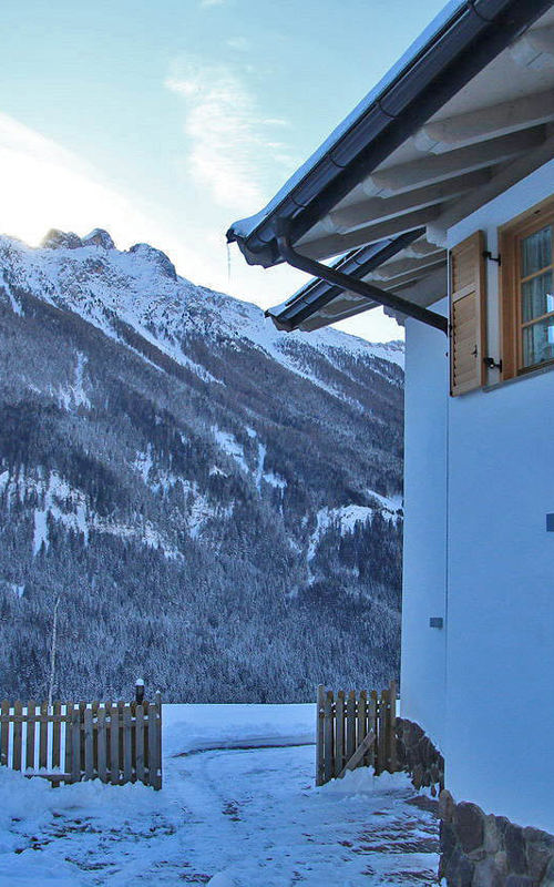 House with garden & snow-covered mountain landscape