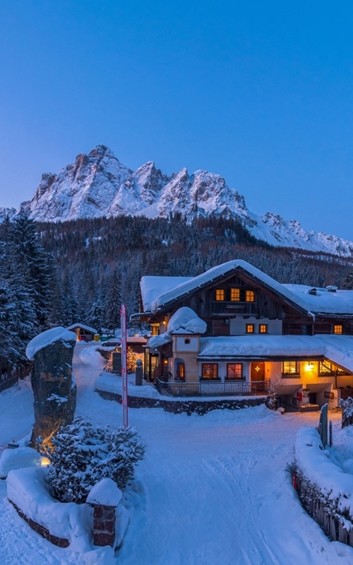 Snow-covered house at sunset in the mountains