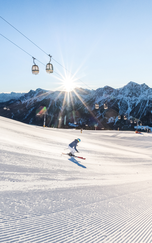 2 skiers on a freshly groomed slope in glorious winter sunshine