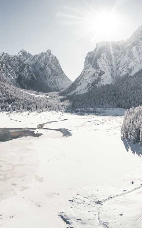 Lake in the middle of the mountains in winter, partly frozen and snow-covered