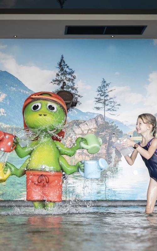 Children playing in a pool in front of a colourful wall